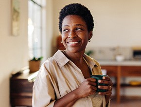 Woman smiling while drinking coffee at home