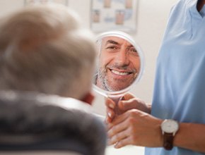 Man smiling at reflection in small mirror