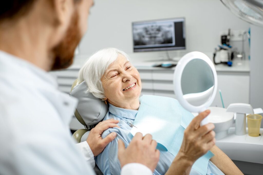 A woman in a dentist chair looking in a mirror.